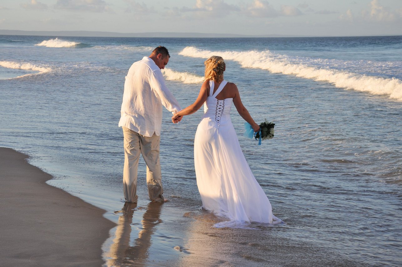 Man and Woman in Wedding Dress Walking on Beach