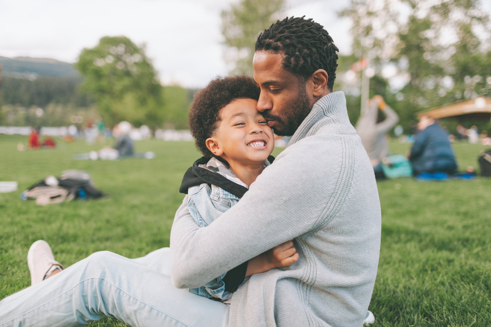 Father and Son Sitting on Grass in the Park